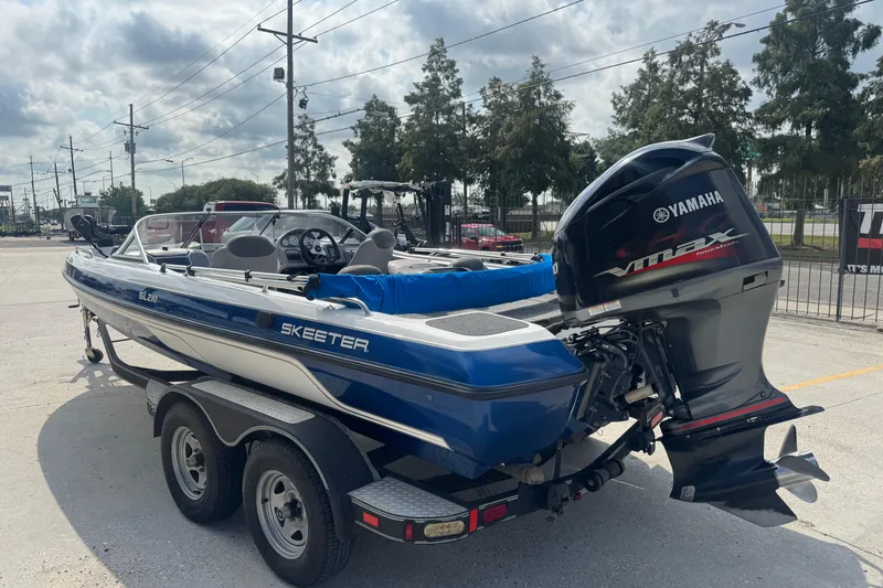 Slide: The Image of 2012 Skeeter SL210 boat with Yamaha VMAX engine on a trailer, parked outdoors. - 4