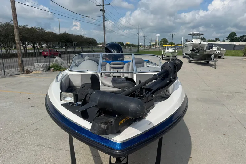 Slide: The Image of 2012 Skeeter SL210 boat with trolling motor, parked outdoors on a sunny day. - 9