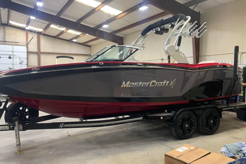 Slide: The Image of 2017 MasterCraft X23 boat in a warehouse, featuring sleek design and dual-axle trailer. - 0