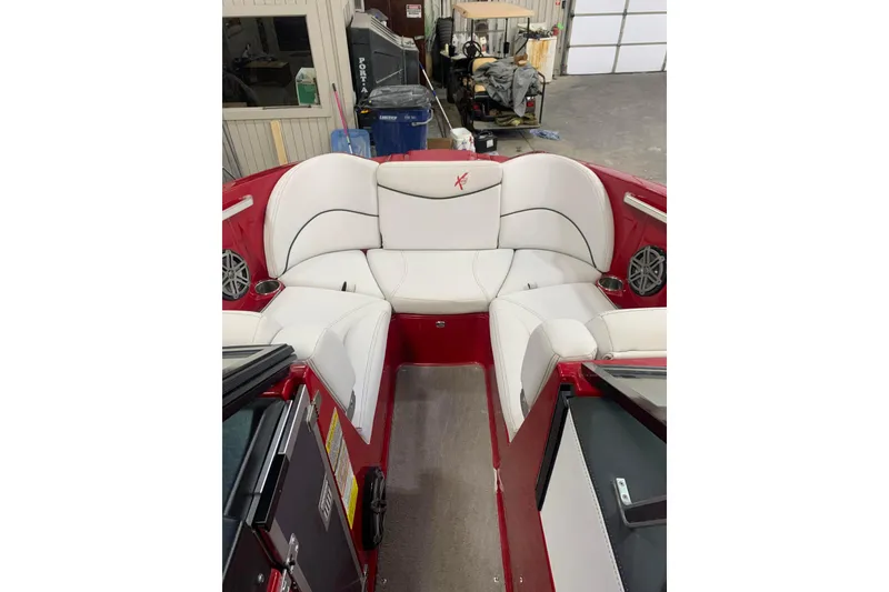 Slide: The Image of 2017 MasterCraft X23 boat interior with white seating and red accents in a garage setting. - 4