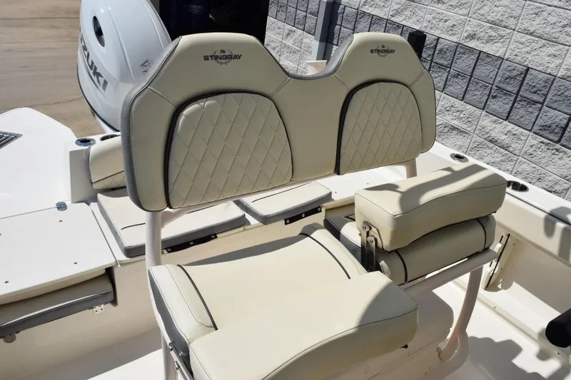 Slide: The Image of 2024 Stingray 216 CC boat interior with beige seating and Suzuki engine. - 10