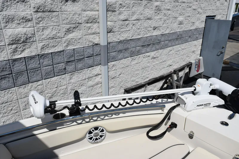 Slide: The Image of 2024 Stingray 216 CC boat with Minn Kota trolling motor, docked near a brick wall. - 18