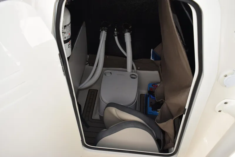 Slide: The Image of 2024 Stingray 216 CC boat interior with compact toilet and storage area. - 26