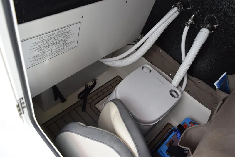 Slide: The Image of 2024 Stingray 216 CC boat interior with portable toilet and storage area. - 27