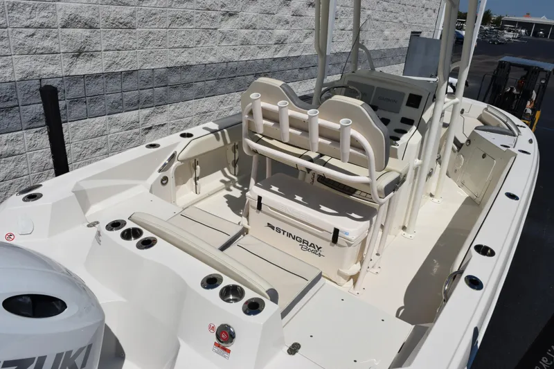 Slide: The Image of 2024 Stingray 216 CC boat interior with seating and control panel, docked outdoors. - 7
