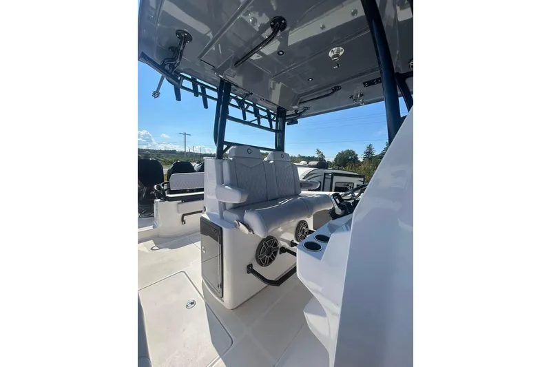 Slide: The Image of 2023 Fountain 38TE CC boat interior with seating and storage, parked outdoors under clear sky. - 16