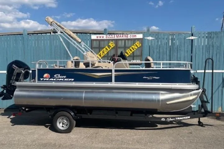 The Image of 2024 Sun Tracker Bass Buggy 18 DLX pontoon boat on trailer, parked outdoors. - 0