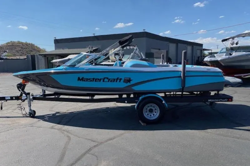 Slide: The Image of 2018 MasterCraft ProStar boat on trailer, parked outdoors under clear sky. - 0