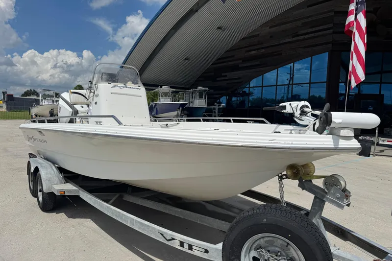 Slide: The Image of 2005 Bay Stealth 2230 boat on trailer, parked outdoors near a modern building. - 5
