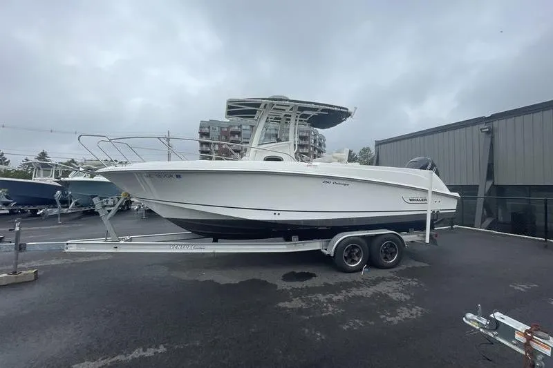 Slide: The Image of 2012 Boston Whaler 250 Outrage boat on trailer, parked outdoors on a cloudy day. - 3