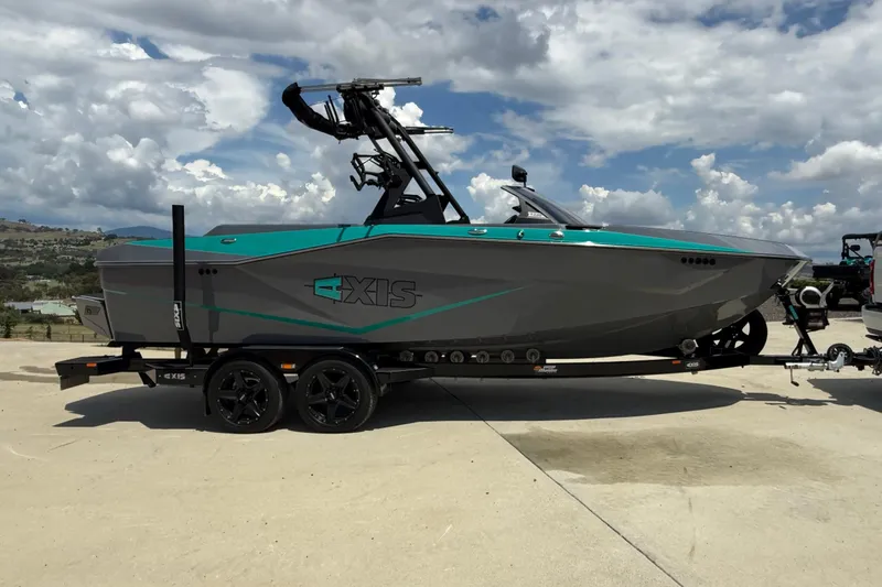 Slide: The Image of 2022 Axis T220 boat on trailer under cloudy sky, side view. - 2