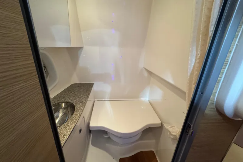 Slide: The Image of 2015 Chaparral 327 SSX boat bathroom with compact toilet and sink. - 15
