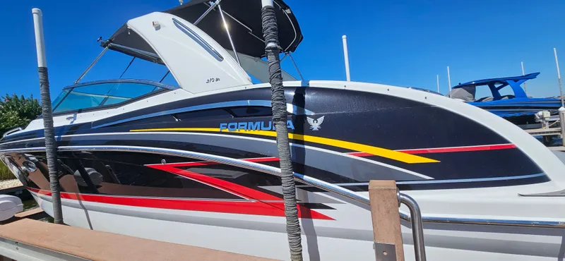 Slide: The Image of 2011 Formula 310 Bowrider boat with colorful stripes docked under clear blue sky. - 16