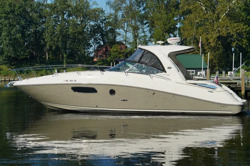 The Image of 2010 Sea Ray 370 Sundancer yacht docked on calm water, surrounded by trees. - 0