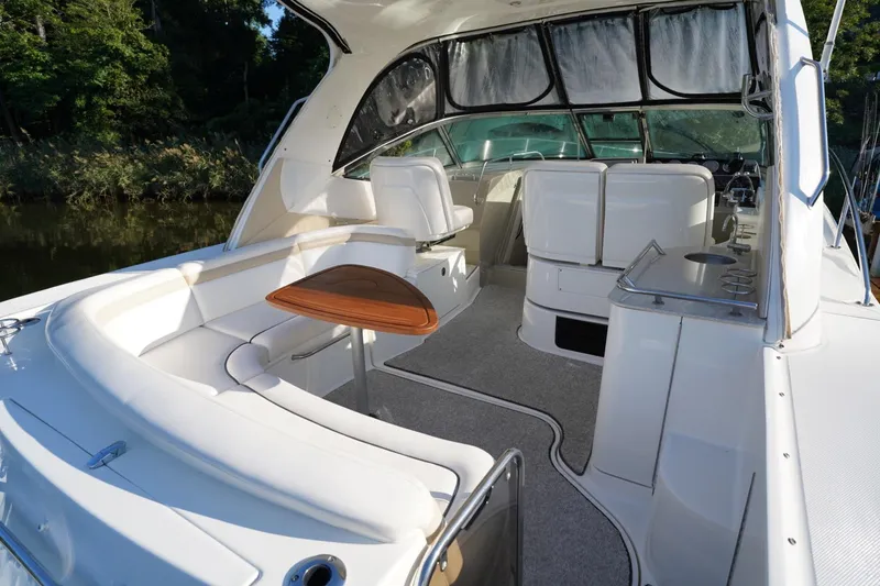 Slide: The Image of 2010 Sea Ray 370 Sundancer boat interior with seating and table, surrounded by lush greenery. - 18