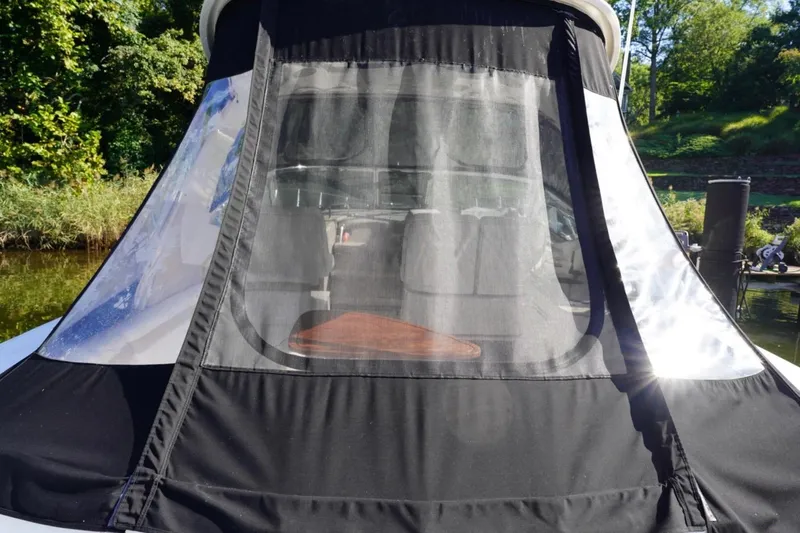 Slide: The Image of 2010 Sea Ray 370 Sundancer with black canvas cover, docked near lush greenery. - 19