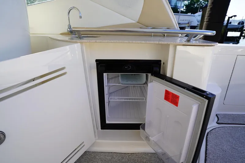 Slide: The Image of 2010 Sea Ray 370 Sundancer yacht kitchenette with open mini fridge and sink. - 39
