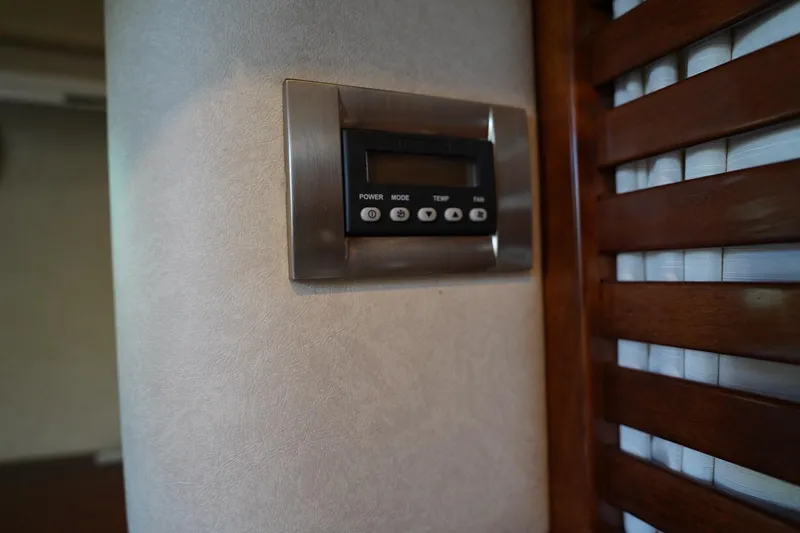 Slide: The Image of Thermostat control panel inside 2010 Sea Ray 370 Sundancer yacht, near wooden blinds. - 64