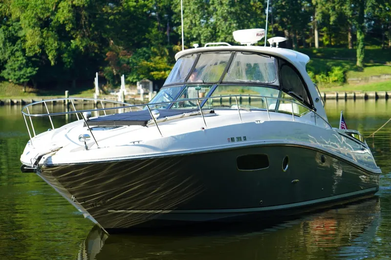 Slide: The Image of 2010 Sea Ray 370 Sundancer yacht on calm water, surrounded by lush greenery. - 8