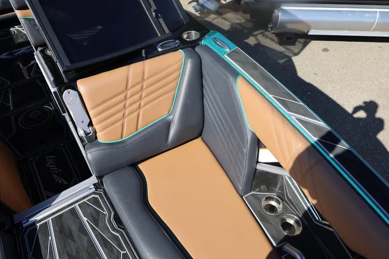 Slide: The Image of 2024 Tigé Ultré 25ZX boat interior with tan and black seating, cup holders, and stylish design. - 25