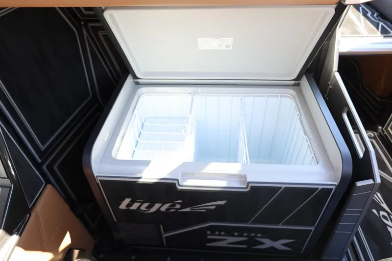 Slide: The Image of 2024 Tigé Ultré 25ZX boat cooler, open with spacious interior, black and white design. - 43
