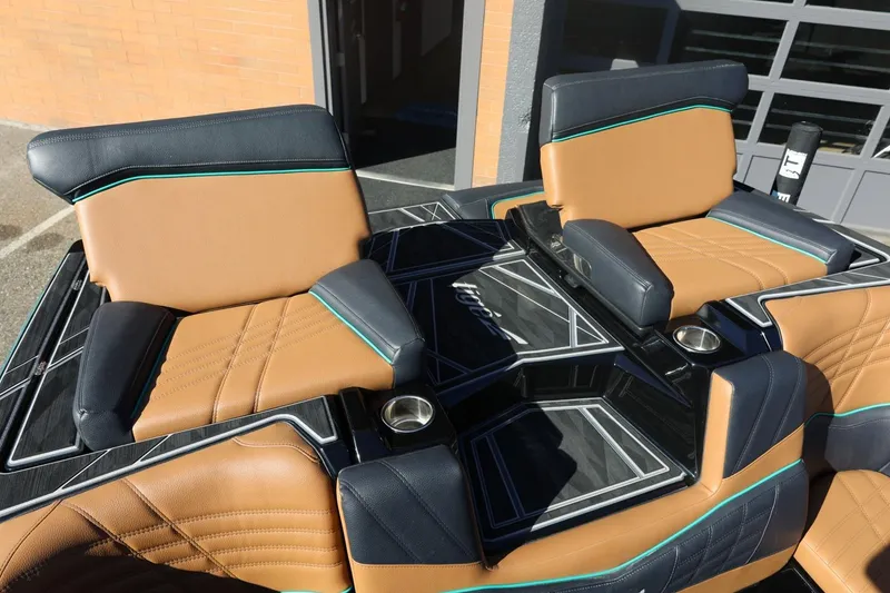 Slide: The Image of 2024 Tigé Ultré 25ZX boat interior with tan and black seating, featuring cup holders. - 60