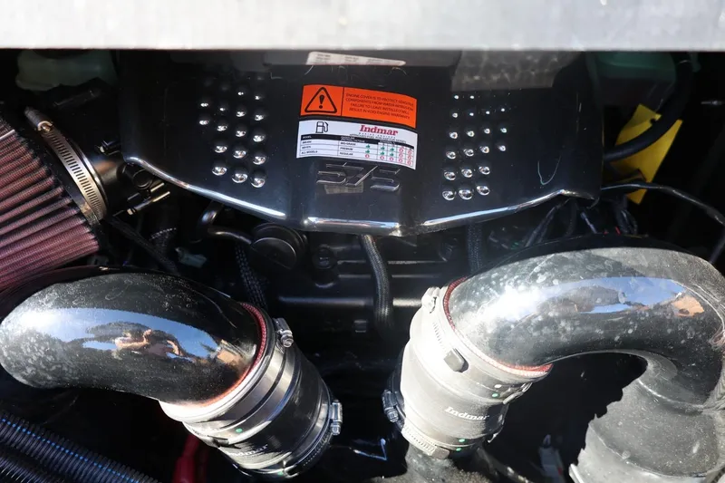 Slide: The Image of 2024 Tigé Ultré 25ZX engine close-up with Indmar components and warning label. - 70