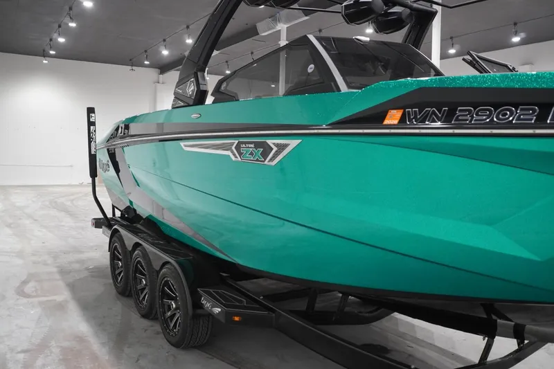 Slide: The Image of 2024 Tigé Ultré 25ZX boat in showroom, vibrant teal color, on a trailer. - 75