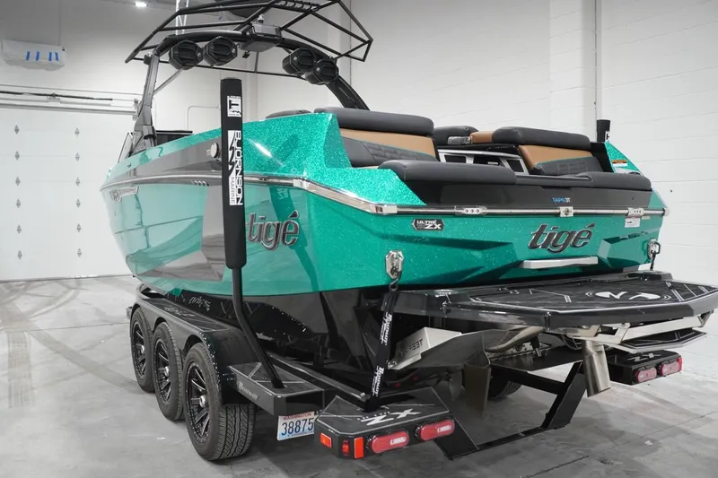 Slide: The Image of 2024 Tigé Ultré 25ZX boat in a showroom, featuring a sleek design and vibrant teal color. - 77