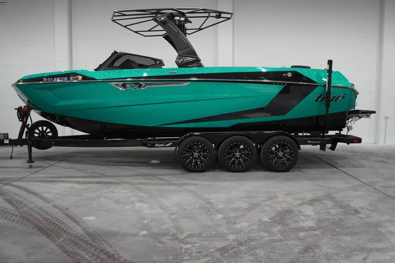 Slide: The Image of 2024 Tigé Ultré 25ZX boat in vibrant teal on a trailer, showcased indoors. - 80