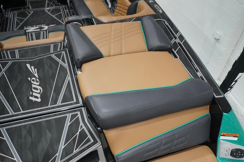 Slide: The Image of 2024 Tigé Ultré 25ZX boat interior with tan and gray seating, geometric flooring. - 83