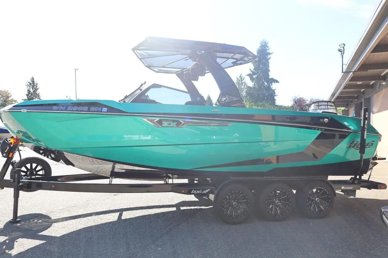 Slide: The Image of 2024 Tigé Ultré 25ZX boat on trailer, vibrant teal color, parked outdoors. - 9