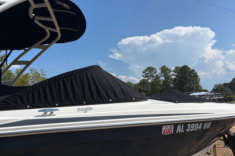 Slide: The Image of 2019 Chaparral 21 H2O Sport boat with black cover, parked outdoors under a blue sky. - 4