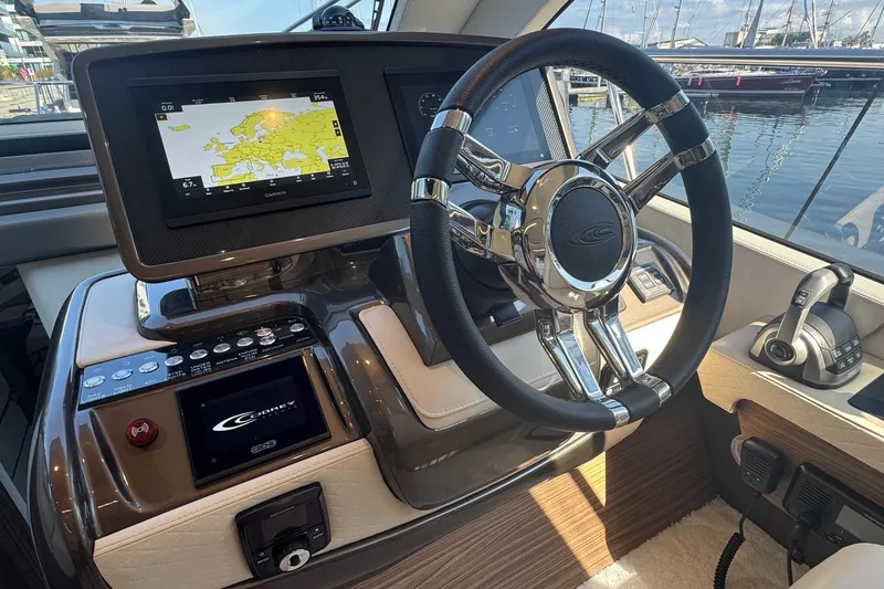 Slide: The Image of 2026 Cobrey 45 FLY yacht helm with navigation display and sleek steering wheel. - 7