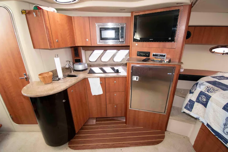 Slide: The Image of 2011 Cruisers Yachts 360 Express interior with kitchenette, TV, and wooden cabinetry. - 12
