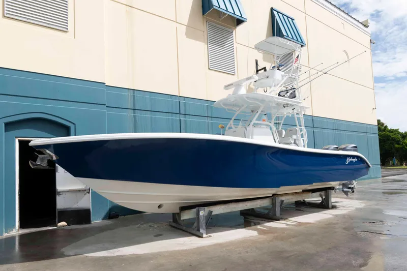The Image of 2018 Yellowfin 32 Offshore boat with blue hull, docked near a building. - 0