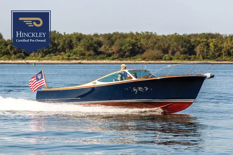 The Image of 2003 Hinckley T29R boat cruising on water, certified pre-owned, with American flag. - 0