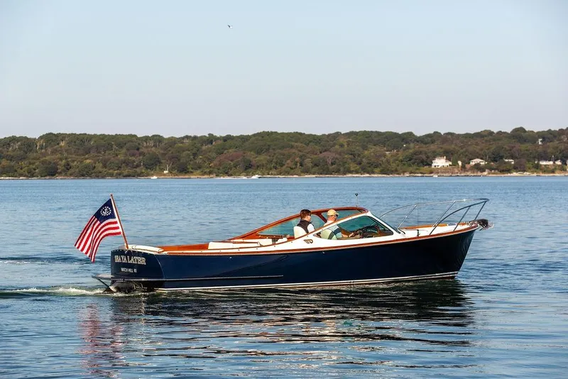 Slide: The Image of 2003 Hinckley T29R boat cruising on calm water with American flag, scenic background. - 14