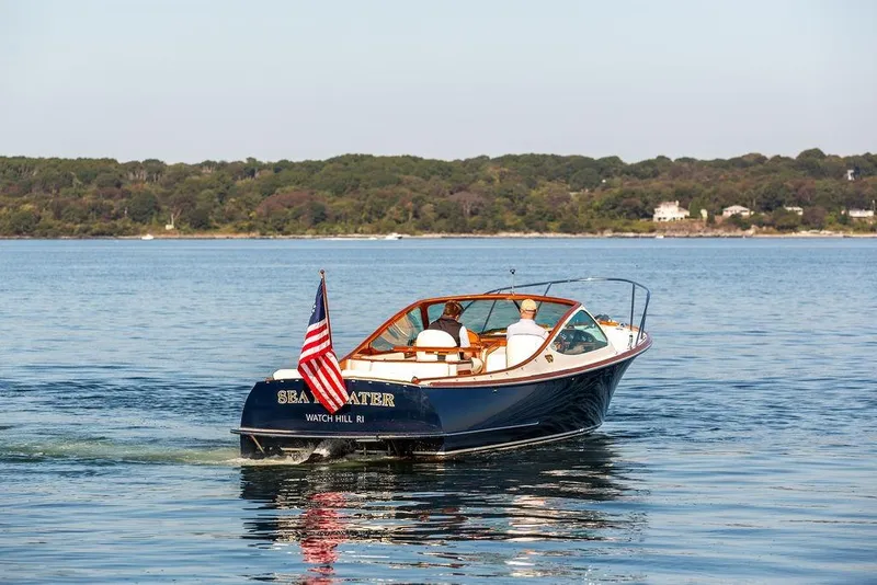 Slide: The Image of 2003 Hinckley T29R boat cruising on calm water with American flag. - 15