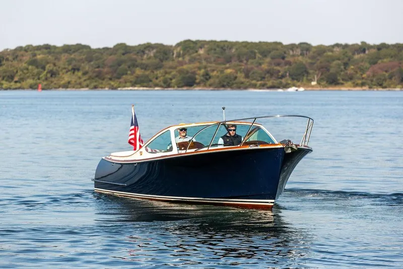 Slide: The Image of 2003 Hinckley T29R boat cruising on a calm lake with scenic background. - 2