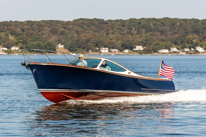 Slide: The Image of 2003 Hinckley T29R boat cruising on a lake with American flag, scenic background. - 22