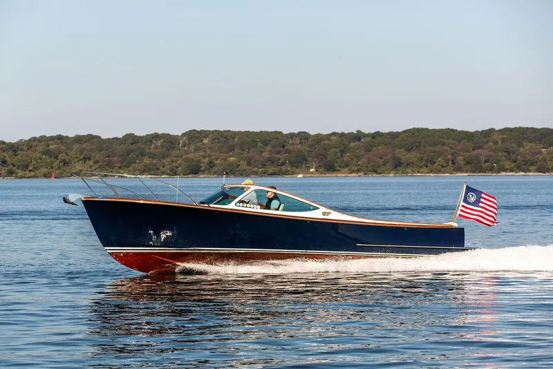 Slide: The Image of 2003 Hinckley T29R boat cruising on a calm lake with forested shoreline. - 23