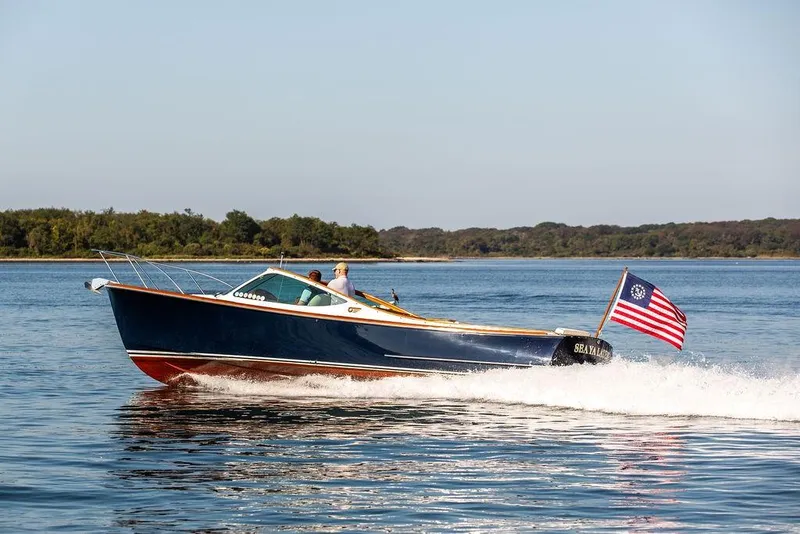 Slide: The Image of 2003 Hinckley T29R boat cruising on a calm lake with American flag. - 24