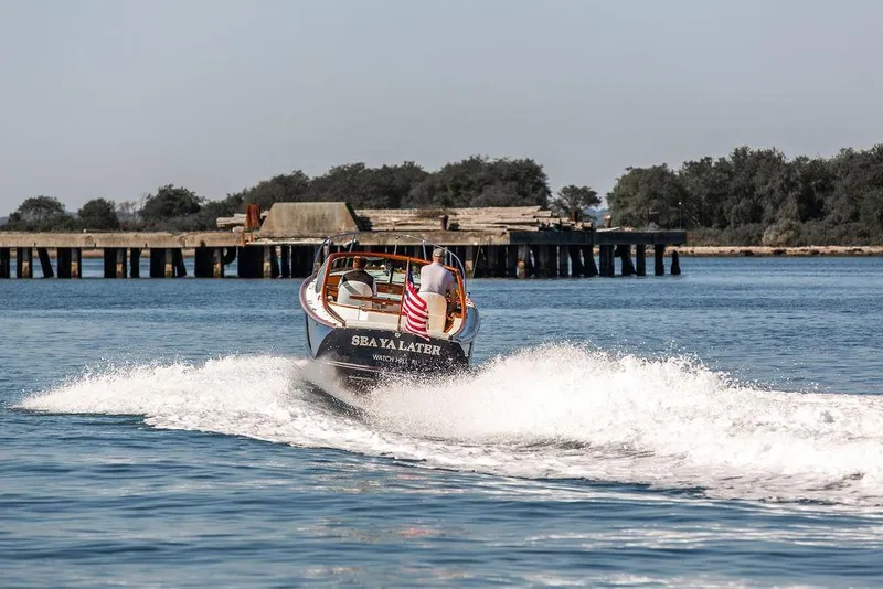 Slide: The Image of Hinckley T29R 2003 boat cruising on water near a pier, American flag displayed. - 26