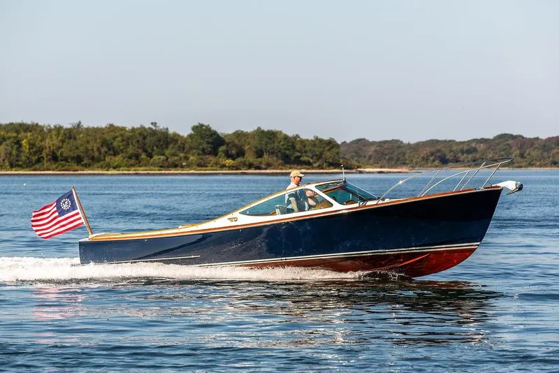 Slide: The Image of 2003 Hinckley T29R boat cruising on a calm lake with American flag. - 27