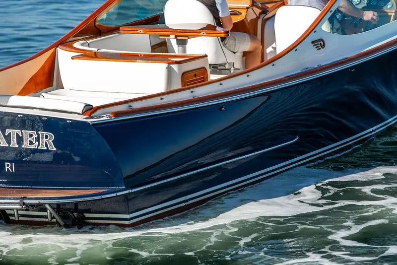 Slide: The Image of 2003 Hinckley T29R boat cruising on water, featuring elegant wood and white seating. - 29