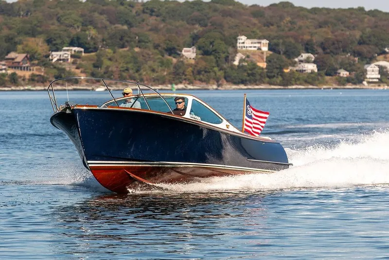 Slide: The Image of 2003 Hinckley T29R boat cruising on a scenic lake with American flag. - 3