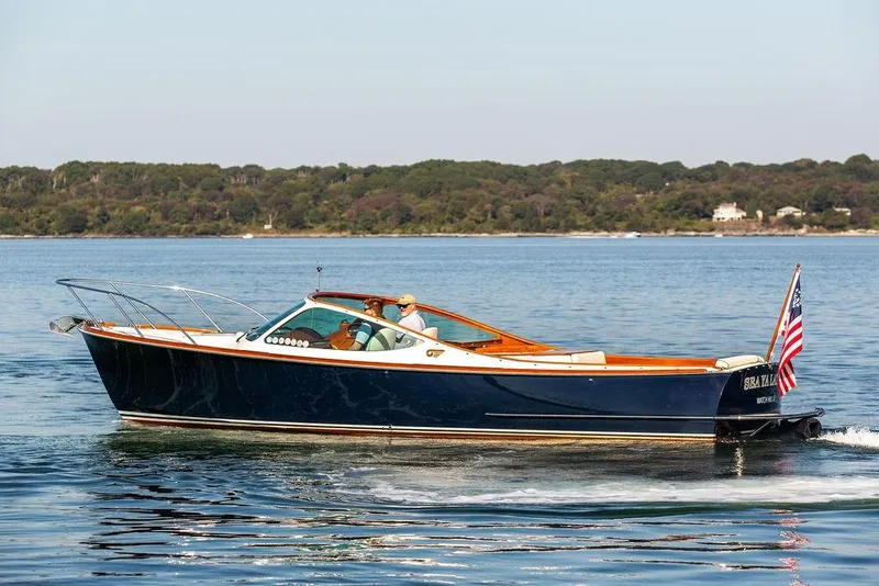 Slide: The Image of 2003 Hinckley T29R boat cruising on calm water with scenic shoreline background. - 18