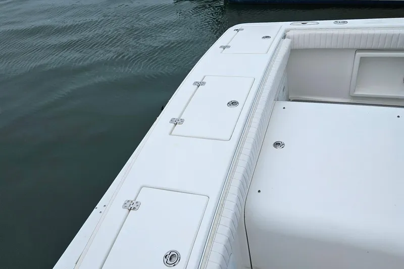 Slide: The Image of 2005 Topaz 24 Silverhawk boat deck with storage compartments, docked on calm water. - 11