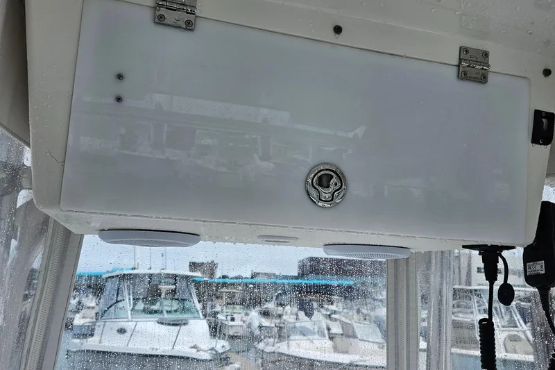 Slide: The Image of 2005 Topaz 24 Silverhawk boat interior with storage compartment and marina view. - 15